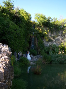 Photo of a bride having her photo taken in front of a waterfall.