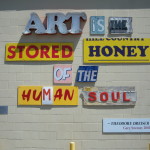 Photo of artwork by Gary Sweeney outside of the San Antonio Museum of Art that reads "Art is the stored honey of the human soul." (Quote by Theodore Dreiser.)
